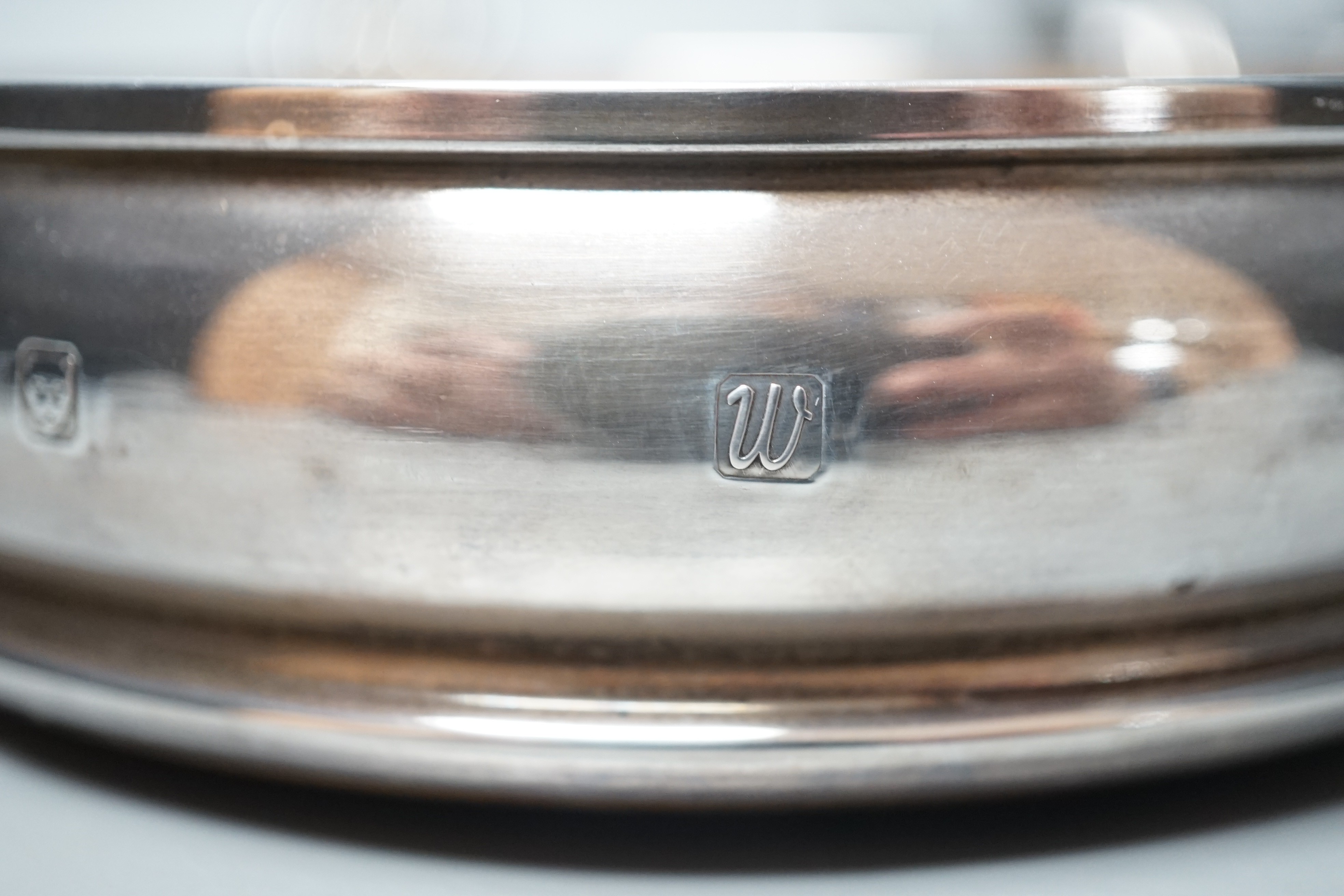 A modern silver mounted wine coaster, London, 1996, diameter 12.4cm, an earlier pierced silver bonbon dish and a pair of plated candlesticks.